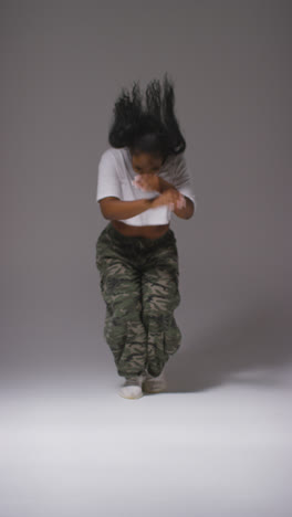 Vertical-Video-Studio-Portrait-Shot-Of-Young-Woman-Dancing-In-Spotlight-Against-Black-Background-1